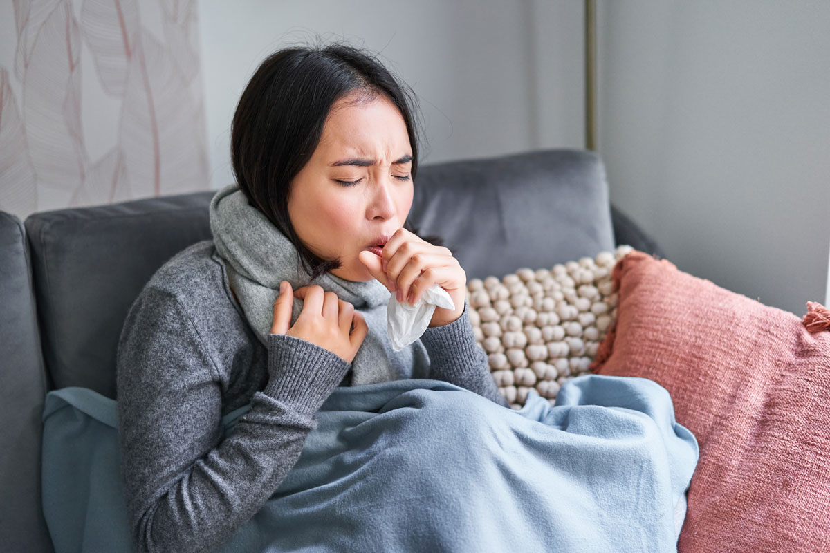 woman coughing feeling sick sitting blanket with scard cold apartment saving heati